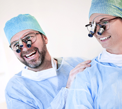 Two dentists wearing loupes and laughing